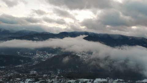 Wonderful large mountain skyline and cloudscape on winter day. Aerial view of beauty mountain range and snowy countryside.