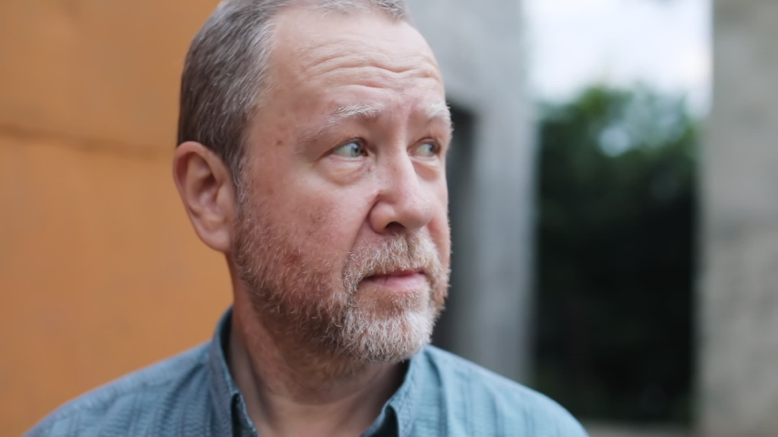 Portrait of attractive grandfather smiling at camera outdoors. Happy old man with smiling face expression.
