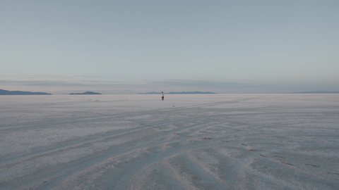 Young attractive female tourist walking on a surface of a Bonneville salt lake flats. 4K UHD 60 FPS SLOW MOTION