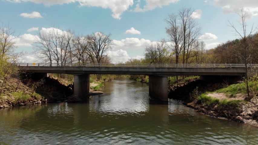 Fly over of a bridge revealing a river in early spring