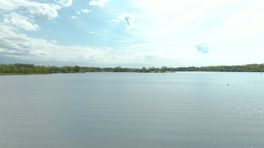 A fast moving shot with a vertical panning motion over water in a small suburban national park lake in the western suburbs of Chicago, Illinois near Lemont, IL. Tampier Slough lake.
