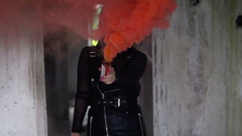 Brutal girl with red smoke in an abandoned building. Model in black leather clothes