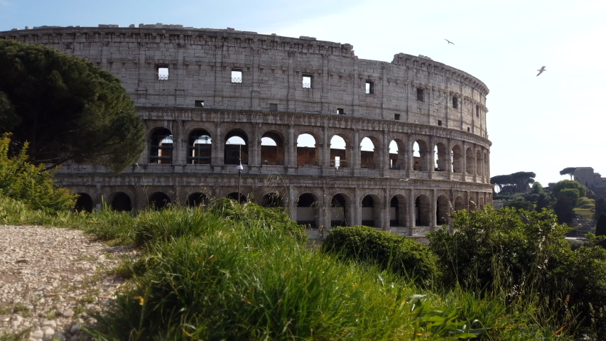 The colosseum from an higher side on a sunny spring day. Time-lapse, over 10 minutes. Cars are passing by. People are walking on the sidewalk. motion lapse from left to right.