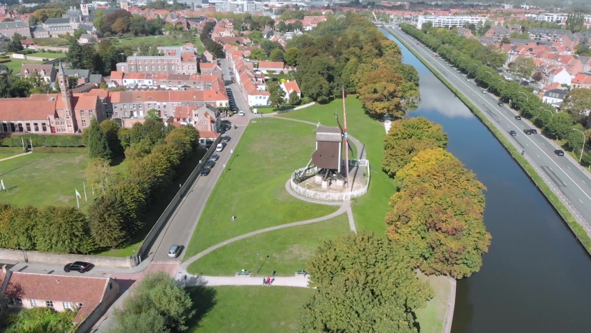 Drone aerial view of river and windmill in city during sunny day