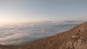Aerial FPV footage of paraglider riding down a mountain.
