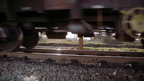 Close up of train wheels and wagons of an ore train pass by the camera.