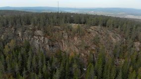 Drone footage flying over a cliff towards a watch-out tower and a forest with two cellphone antenna masts. Filmed in realtime at 4k.