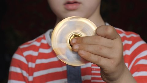Spinning toy, spinner, in the hands of a fair-haired boy.