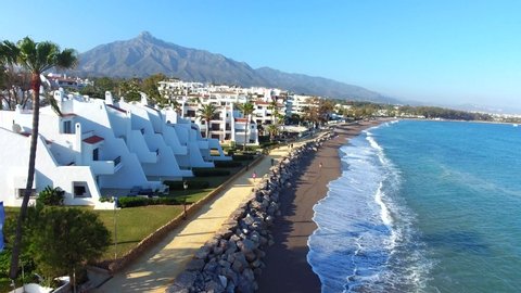 Aerial view flying over coast line of golden mile, marbella,Spain.
area known as the costa del sol, known for vacation and holidays.shot shows beach people walking and mountain perfect composition