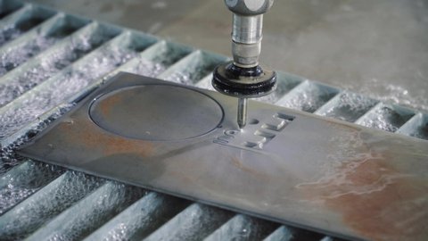 Waterjet metal cutting. Hydroabrasive high pressure CNC machine is cutting out a shape on a metal sheet