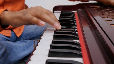 Indian musician playing keyboard of harmonium.