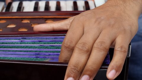 Closeup shot of a musician using his hand to pump the bellows to create the sound of the harmonium.
