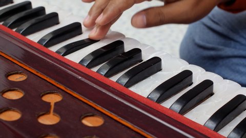 Closeup shot of hands of musician playing keys of harmonium.