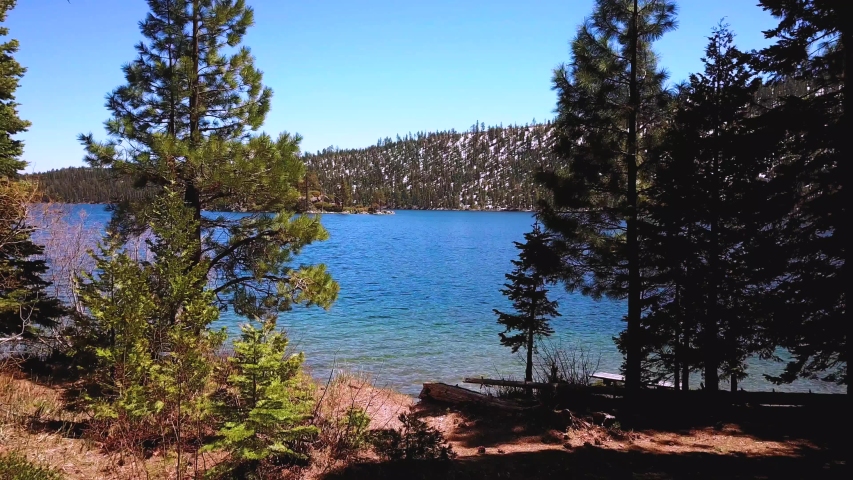 Aerial drone, flying through tress, Lake Tahoe at Emerald Bay, snow mountains, sunny day, Nevada, USA