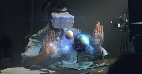 Slow motion of an astronomy scientist using sophisticated and futuristic technology vr glasses with augmented reality holograms to analyze the planets movements in universe.