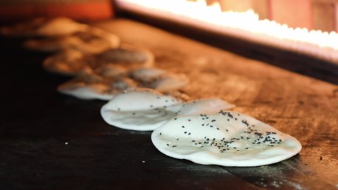 Pita Bread In Oven. Pita or pide bread covered with egg and sesame on on wooden oar in oven or stove. Bakery or bakehouse concept image.