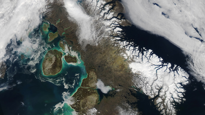 Rotating clouds over ocean sea and winter aerial satellite view mountains and snow. Baffin island and Foxe basin in Canada. Contains public domain image by Nasa