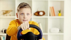 selective focus of emotional schoolboy holding toy steering wheel and becoming sad after playing video game