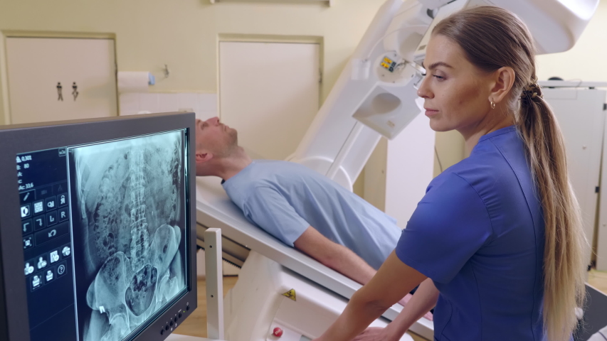 Beautiful Female Technician ajusts X-ray Machine, man lying Royalty-Free Stock Footage #1030105730