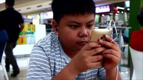 Hand held video shot of a young Asian boy using a smartphone.