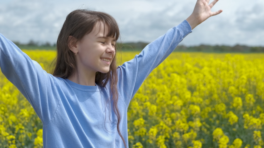 Happy child in a field of flowers. The little girl is spinning on the rapeseed field.