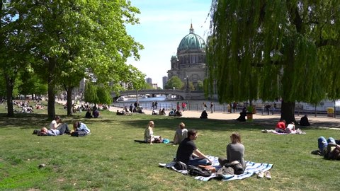 Berlin, Germany - May 12, 2019. People sunbathe on the lawn near the Berlin Cathedral and the Sprea river