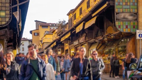Florence, Tuscany, Italy. View of The Ponte Vecchio with a blurred crowd of people. "Old Bridge" is a medieval stone closed-spandrel segmental arch bridge over the Arno River. Time lapse. Zoom effect