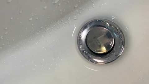 Ultra slow motion of water drops dropping into bathroom sink. Closeup drops of water. Saving water. Clean water problem.