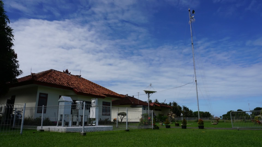 Timelapse a group of white cirrus and altocumulus clouds in the bright blue sky, Time lapse shot of white cirrus and altocumulus passing overhead, above a house building and green grass in Indonesia