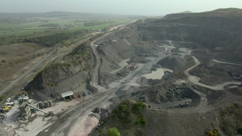An aerial view of a working concrete, asphalt and aggregate quarry, near Kirkcaldy, Fife, Scotland. Tracking across the quarry face.