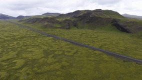Aerial view of road highway through mossy outdoor lava field terrain in Iceland, Europe. Nature scenery drone camera footage.