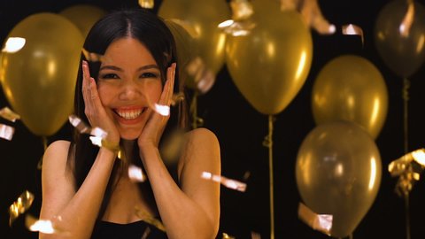 Smiling birthday girl enjoying party under falling confetti, sweet sixteen party