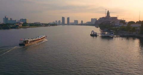 following public boat filled with passengers early in the morning in Bangkok, Asia with panorama of skyscrapers