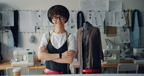 Portrait of happy young lady fashion designer smiling standing in workshop alone looking at camera. Small business owner and successful youth concept.