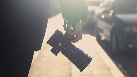 Professional photojournalist holding camera, walking on street, paparazzi spying