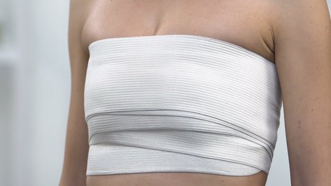 Woman wrapped in elasto-fit breast touching chest, painful surgical suture