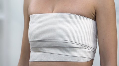 Female patient touching breast in chest compression wrap, lifting surgery