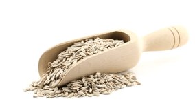 Organic, raw, shelled sunflower seeds in wooden scoop on wood plate rotating