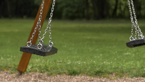 Empty playground after rain. Swing got wet in raindrops. Summer or spring rainy day. No people. No children.