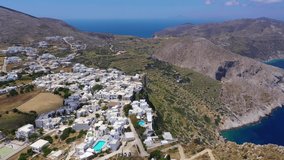 Aerial drone video of iconic and picturesque main village (chora) of Folegandros island featuring castle and built on top of steep hill overlooking the Aegean blue sea, Cyclades, Greece