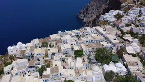 Aerial drone video of iconic and picturesque main village (chora) of Folegandros island featuring castle and built on top of steep hill overlooking the Aegean blue sea, Cyclades, Greece