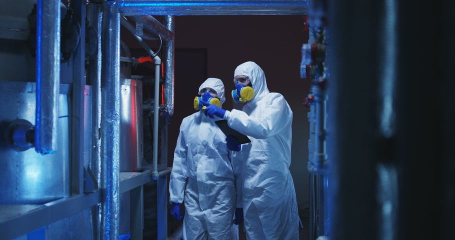Medium shot of two scientists in hazmat suits conducting maintenance work Royalty-Free Stock Footage #1030179113
