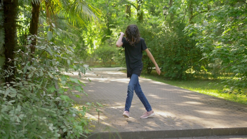 handsome stylish teen boy dancing hip hop in summer park