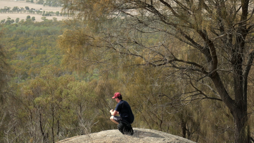 Man looking out from the You Yangs National Park, Victoria Australia. Man takes a drink of water from his canister.