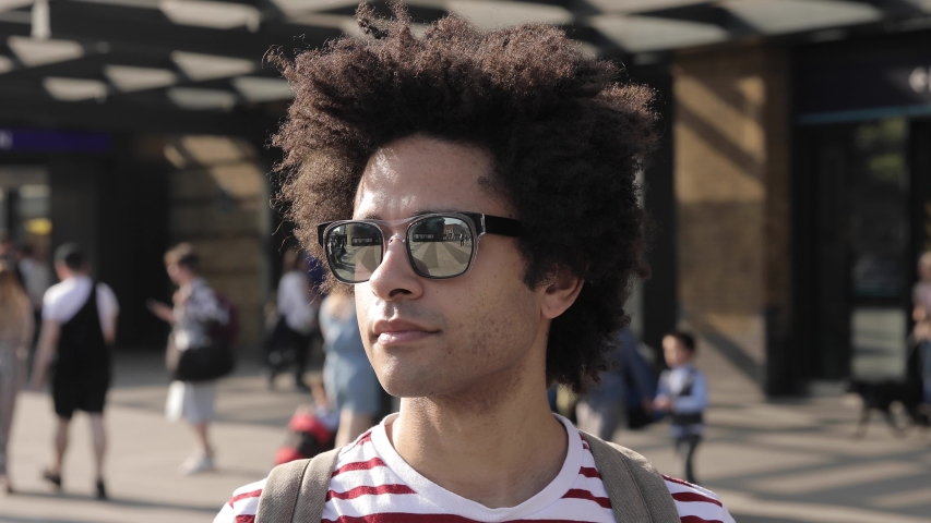 Man portrait in front of busy train station in London - Portrait of mixed race man in the city enjoying his trip and having fun