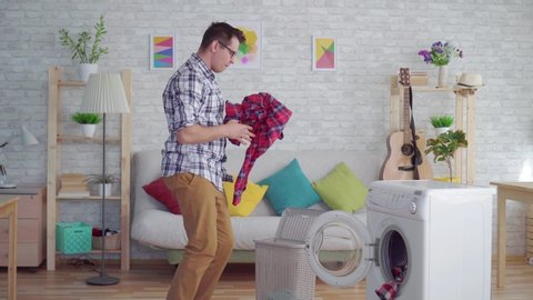 cheerful middle-aged man engaged in household chores washes things and dances