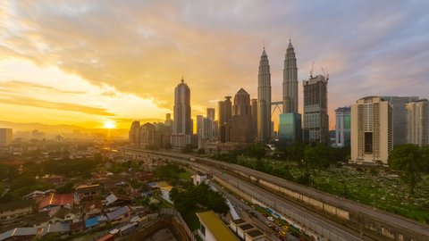 Time lapse: Kuala Lumpur City view during dawn overlooking a city skyline with busy light trails on a expressway in Malaysia. Zoom out motion timelapse.