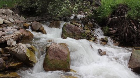 Rough mountain river flows among large stones