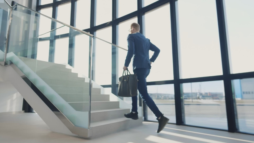 Businessman walking up the stairs hastily. In his hand is a brown leather briefcase