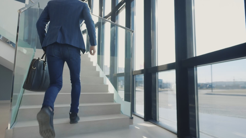 Office manager holding suitcase and running on office stairs